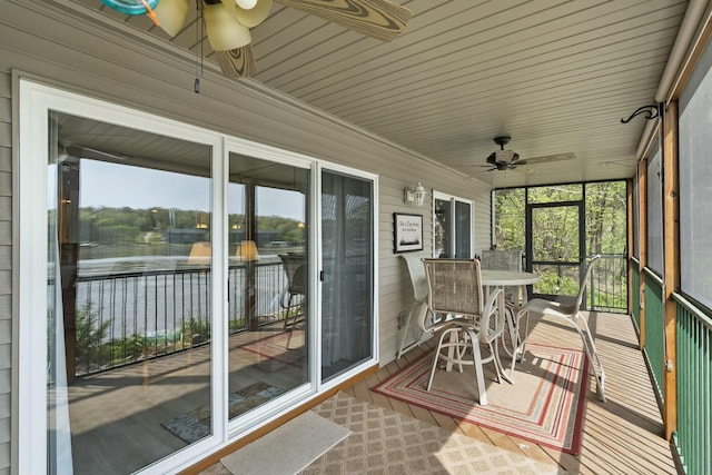 sunroom featuring ceiling fan and a water view