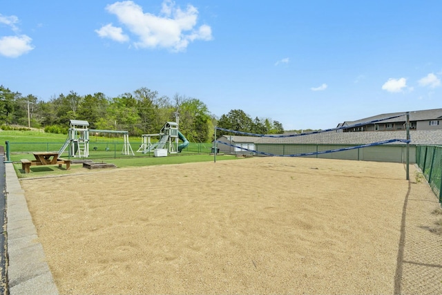 view of community with fence, volleyball court, playground community, and a lawn