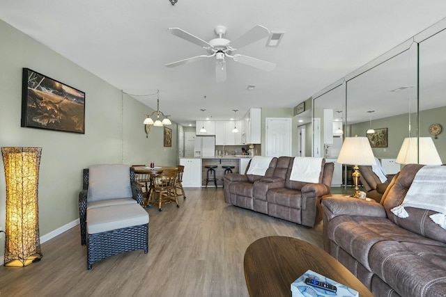 living room with a ceiling fan, visible vents, light wood-style flooring, and baseboards