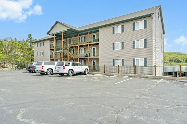 view of building exterior featuring uncovered parking and fence