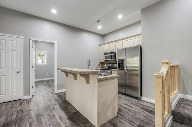 kitchen with stainless steel appliances, backsplash, dark wood-style flooring, a kitchen bar, and visible vents