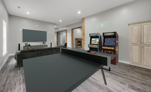 recreation room featuring visible vents, recessed lighting, a glass covered fireplace, baseboards, and light wood-type flooring