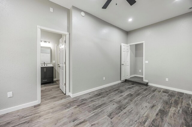 unfurnished bedroom featuring connected bathroom, a sink, wood finished floors, and baseboards