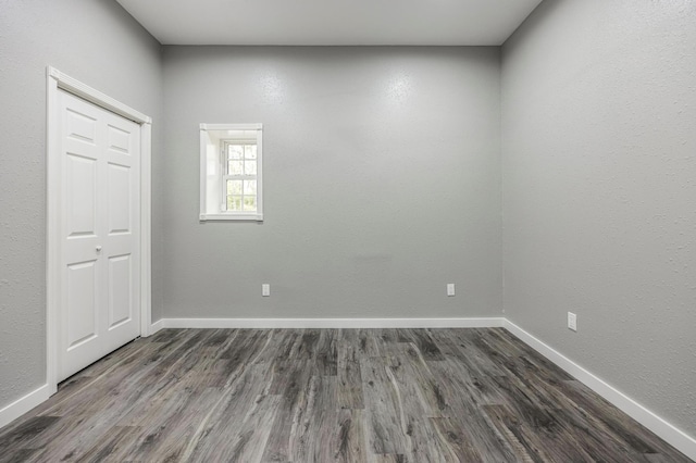 unfurnished room with baseboards and dark wood-type flooring