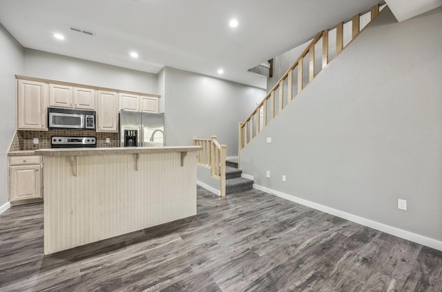 kitchen featuring recessed lighting, stainless steel appliances, a kitchen breakfast bar, and dark wood-style flooring
