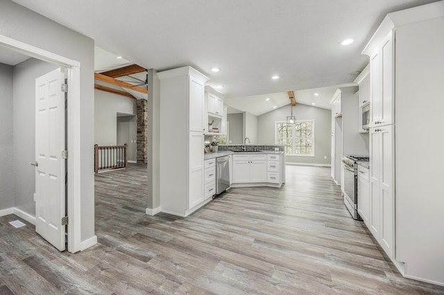 kitchen featuring appliances with stainless steel finishes, baseboards, vaulted ceiling with beams, and a sink