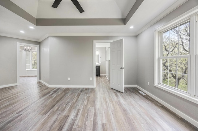 empty room with ceiling fan with notable chandelier, baseboards, wood finished floors, and plenty of natural light
