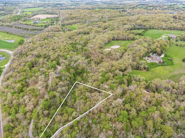 aerial view with view of golf course and a wooded view