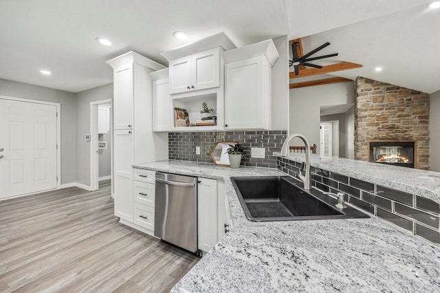 kitchen featuring light stone counters, a sink, light wood-type flooring, dishwasher, and backsplash