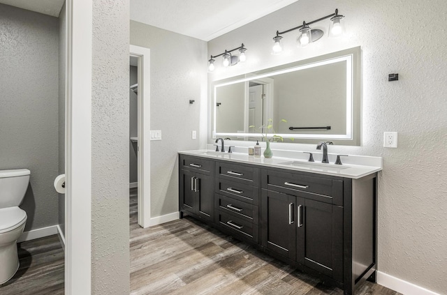 bathroom with toilet, a sink, and wood finished floors