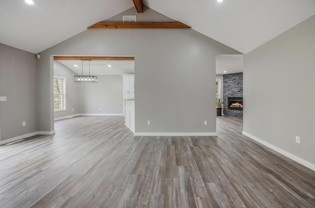 unfurnished living room with recessed lighting, beam ceiling, visible vents, a stone fireplace, and wood finished floors