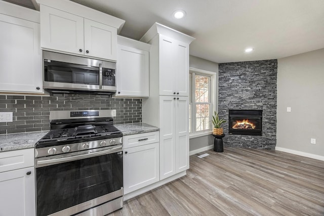 kitchen with appliances with stainless steel finishes, white cabinetry, decorative backsplash, and baseboards