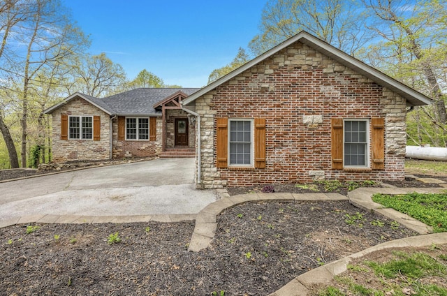 single story home featuring brick siding, driveway, and stone siding