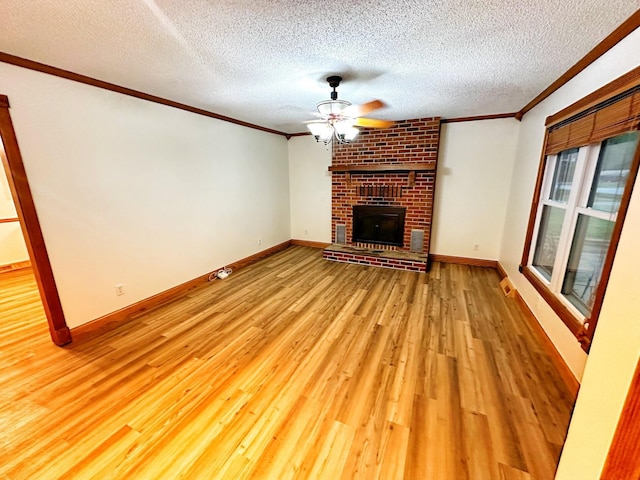 unfurnished living room featuring a brick fireplace, crown molding, a ceiling fan, light wood-style flooring, and a textured ceiling