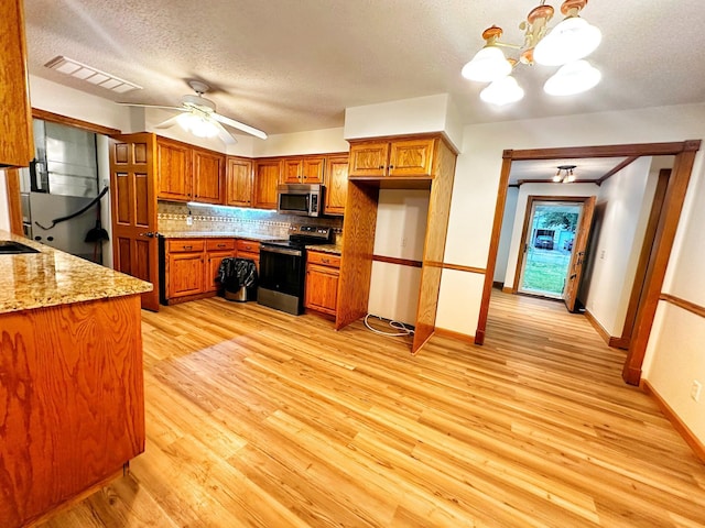 kitchen with a textured ceiling, appliances with stainless steel finishes, visible vents, light wood finished floors, and brown cabinetry