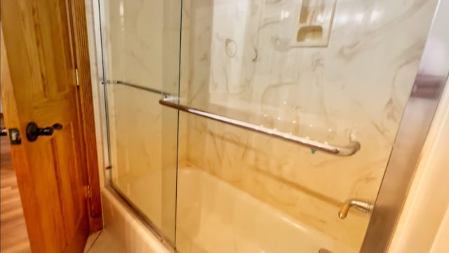bathroom featuring combined bath / shower with glass door