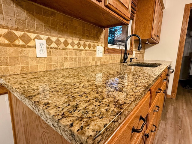 213 W Charles St, Republic, MO 65738 - kitchen view of a sink, brown cabinets, wood finished floors, backsplash, and light stone countertops