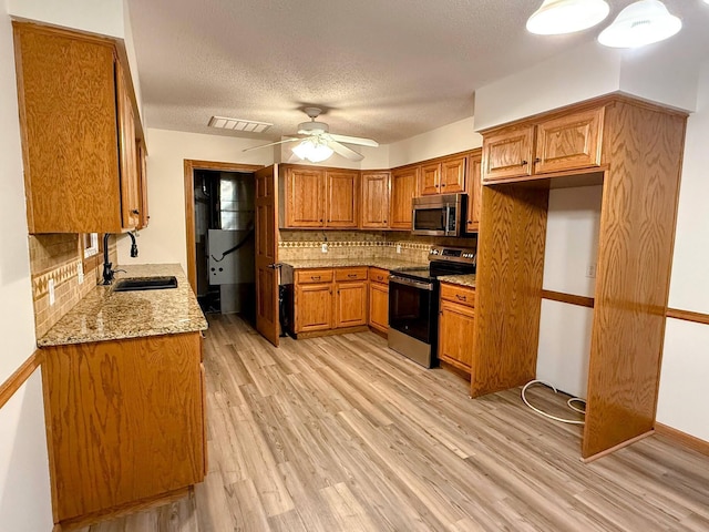 213 W Charles St, Republic, MO 65738 - kitchen featuring appliances with stainless steel finishes, a sink, brown cabinets, tasteful backsplash, and light wood-style flooring