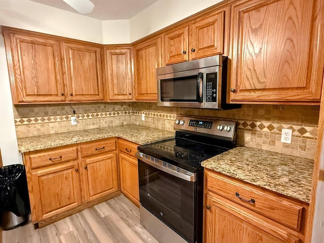 213 W Charles St, Republic, MO 65738 - kitchen featuring appliances with stainless steel finishes, tasteful backsplash, light stone counters, light wood-type flooring, and brown cabinets