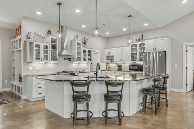 kitchen with a sink, wall chimney range hood, finished concrete flooring, white cabinets, and stainless steel fridge with ice dispenser