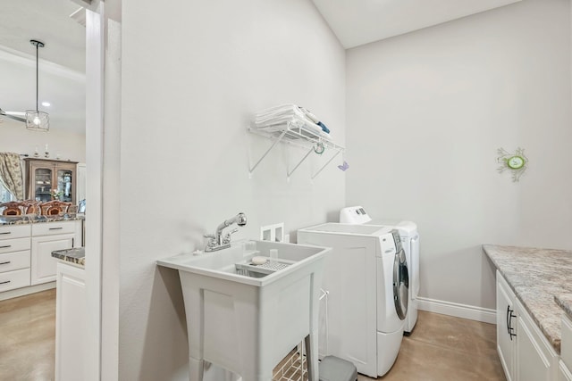 laundry room featuring baseboards, a sink, cabinet space, and washing machine and dryer