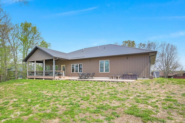 rear view of property with metal roof, a patio, and a yard