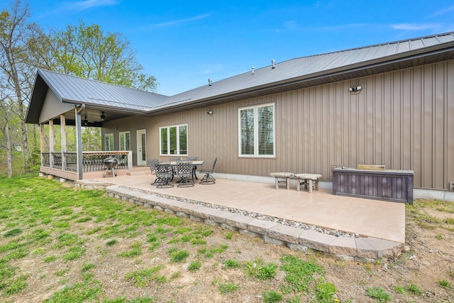 back of house featuring ceiling fan, a patio area, a wooden deck, and metal roof