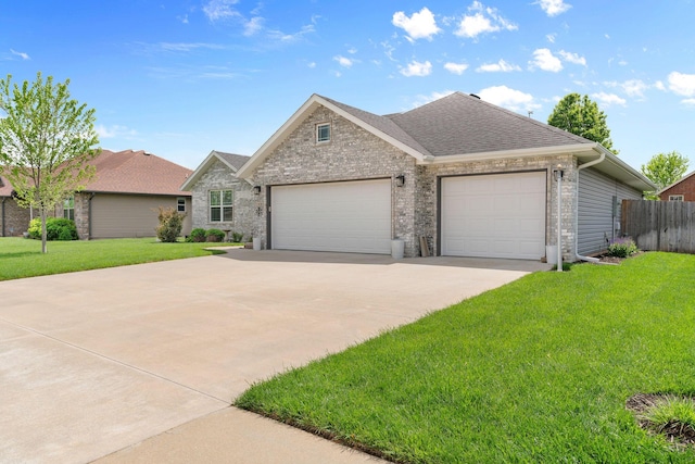 ranch-style home featuring roof with shingles, concrete driveway, a front yard, and an attached garage