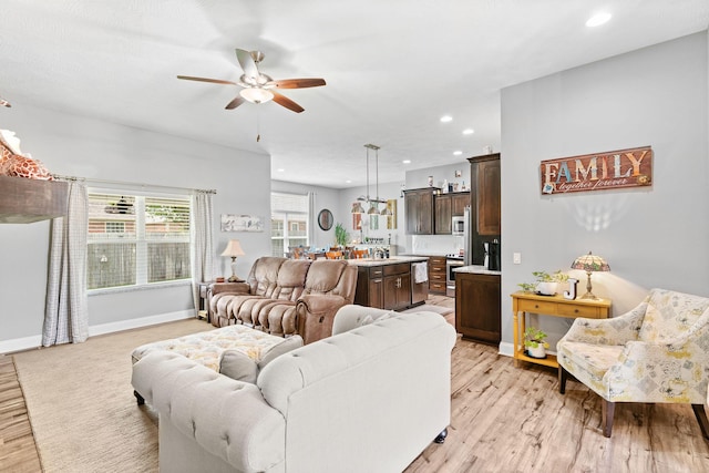living area featuring light wood-type flooring, a ceiling fan, recessed lighting, and baseboards