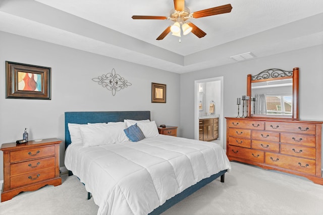 bedroom with visible vents, ensuite bathroom, ceiling fan, and light colored carpet