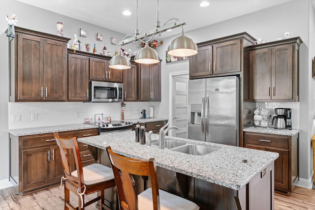 kitchen featuring dark brown cabinetry, stainless steel appliances, backsplash, and a sink