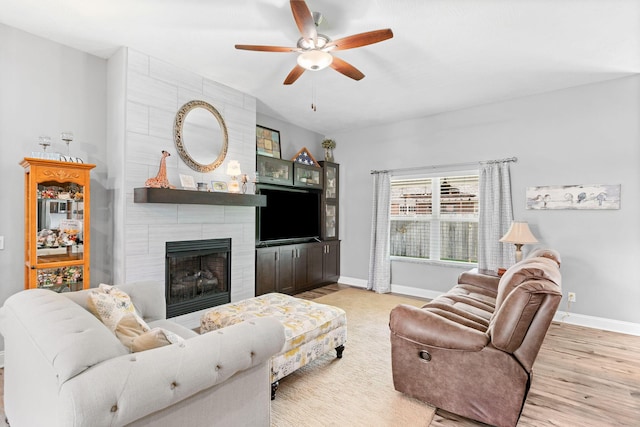 living area with a fireplace, a ceiling fan, light wood-style floors, and baseboards
