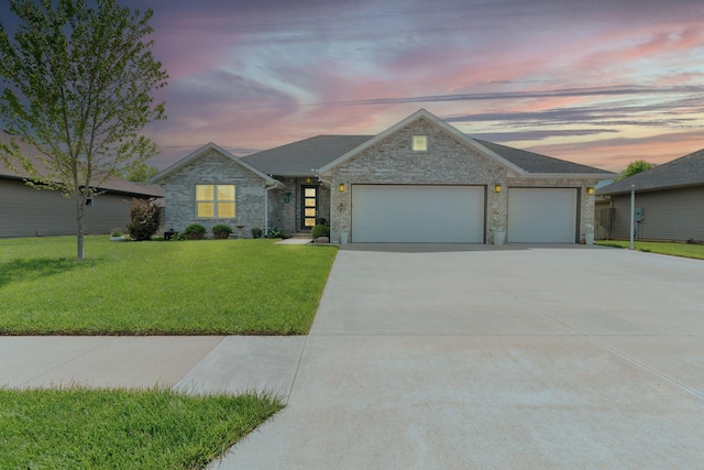 single story home with a garage, driveway, a yard, and stone siding