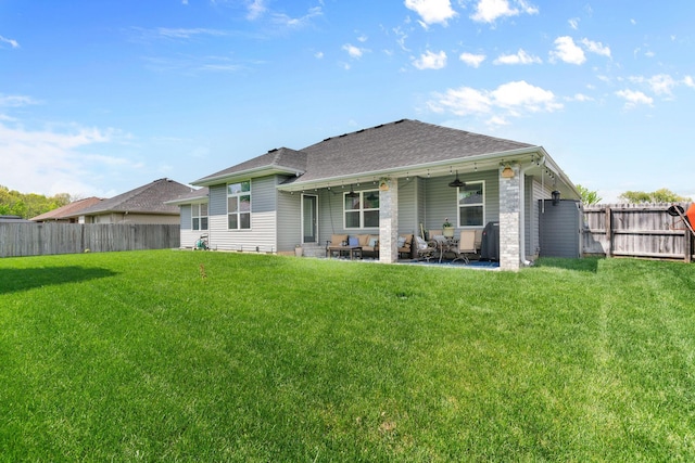 rear view of house featuring a lawn, roof with shingles, and a fenced backyard