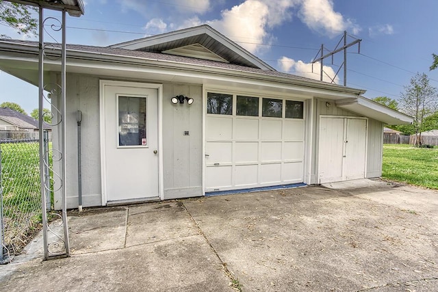 garage with fence and concrete driveway