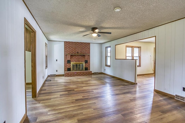 unfurnished living room featuring wood finished floors, ceiling fan, baseboards, visible vents, and a textured ceiling