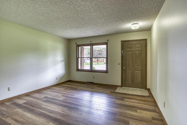 interior space featuring baseboards, visible vents, wood finished floors, and a textured ceiling