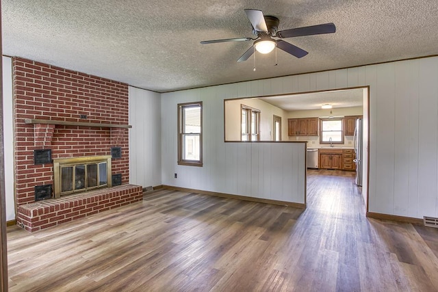 unfurnished living room with a ceiling fan, a sink, wood finished floors, and a textured ceiling