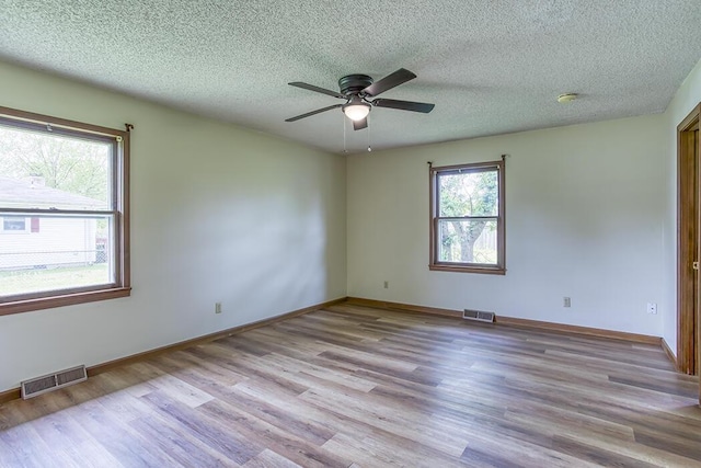unfurnished room featuring wood finished floors, visible vents, and ceiling fan