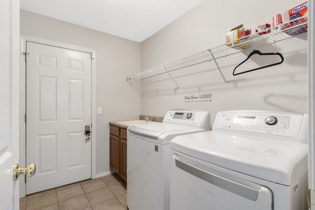 laundry room with light tile patterned floors, washing machine and clothes dryer, cabinet space, and a sink
