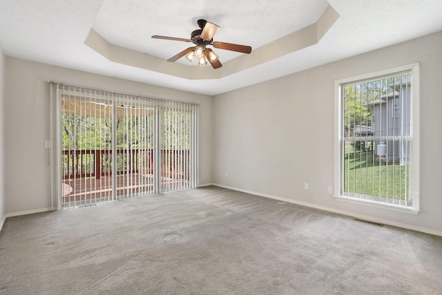 empty room featuring carpet flooring, a ceiling fan, visible vents, and baseboards