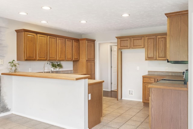 kitchen featuring electric stove, recessed lighting, brown cabinets, a peninsula, and light tile patterned flooring
