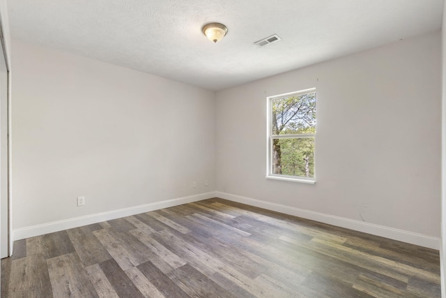spare room featuring visible vents, wood finished floors, and baseboards