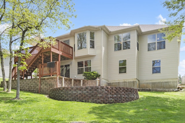 back of property featuring a deck, stairway, a shingled roof, and a lawn