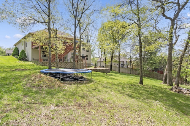 view of yard with a trampoline and fence
