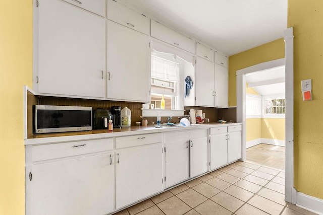 937 S Fremont Ave, Springfield, MO 65804 - kitchen with stainless steel microwave, white cabinetry, a sink, light countertops, and baseboards