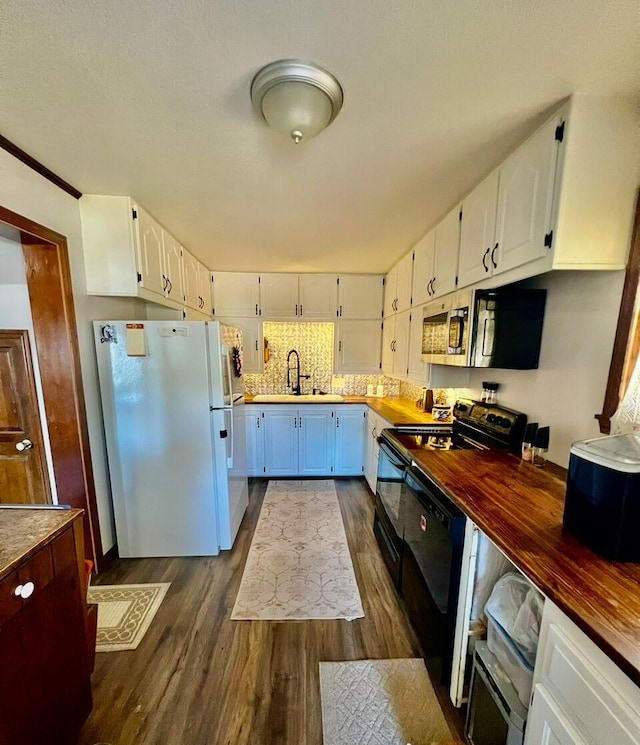 kitchen featuring white cabinets, a sink, dark wood-type flooring, and freestanding refrigerator