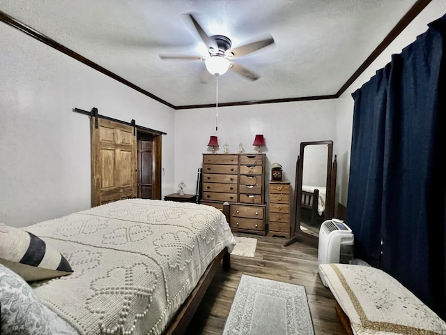 bedroom featuring ornamental molding, ceiling fan, a barn door, and dark wood finished floors
