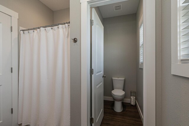 2460 S Durango Dr, Bolivar, MO 65613 - full bath with curtained shower, toilet, visible vents, baseboards, and wood finished floors