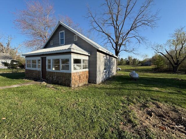 view of side of home with a yard and stone siding